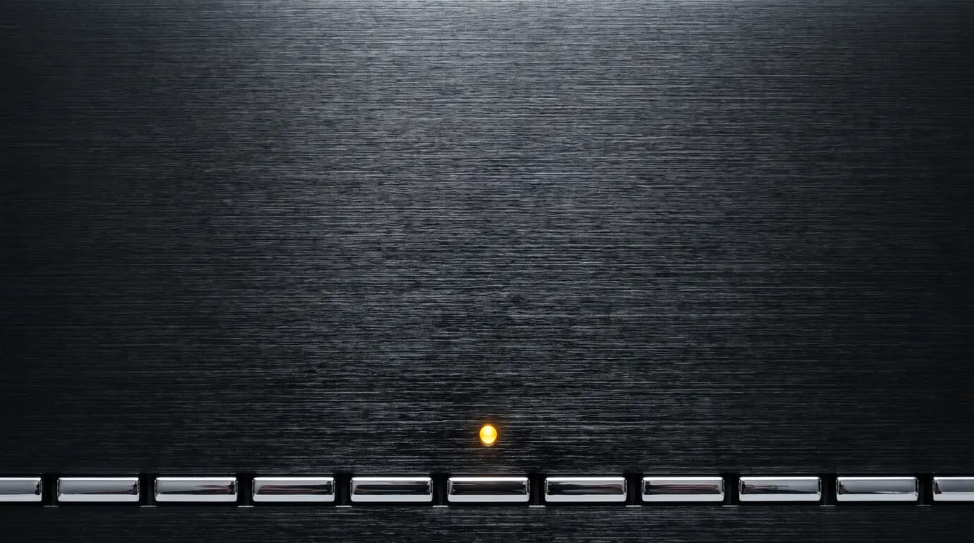 Generated image: macro of a brushed dark hi-fi panel with chrome keys along the bottom edge and one amber lamp lit.